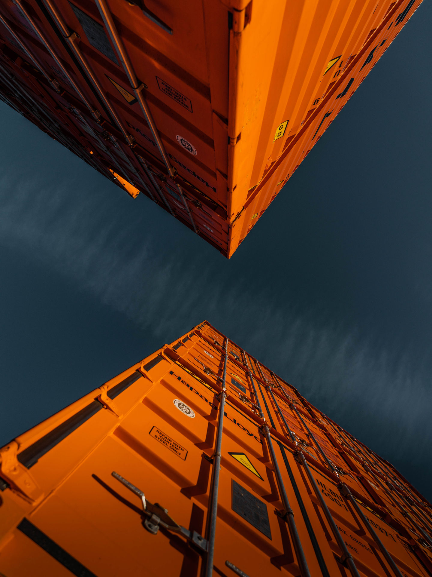 Stacked orange shipping containers against a dark sky